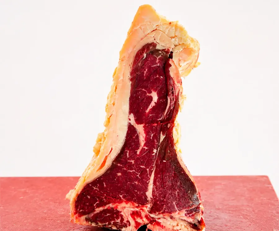 T-bone de vaca de canto sobre la tabla de corte roja